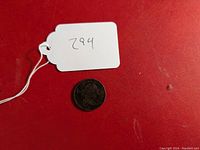 Coin with tag showing lot number on red background