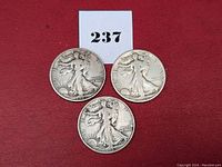 Three Walking Liberty Half Dollar coins front view on a red background, showing Lady Liberty design.
