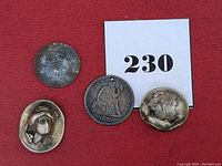Four altered and damaged dimes on red surface with lot number card