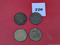 Four US large cent coins arranged on a red background, visibly worn and corroded.