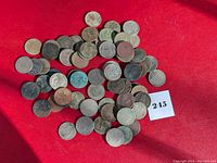Group of over 60 uncleaned US nickels on red background showing various wear and dirt deposits.