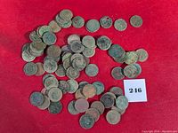 Lot image showing over 75 uncleaned, heavily worn Indian Head cents scattered on red background with visible corrosion and dirt.
