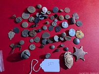 Full collection of badges, buttons, bells and small figurines arranged on red cloth