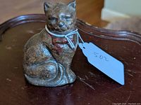 Front view of cast iron seated cat still bank showing the cat's face, red collar, and texture of the iron.