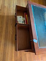Side view of coffee table showing two open pass-through drawers with items inside, drawer pulls visible