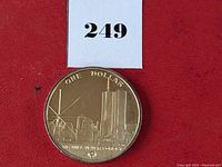 Front side of first coin showing Twin Towers skyline with text 'ONE DOLLAR' and 'WE WILL NEVER FORGET'
