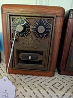 Front view of the oak coin bank showing vintage mailbox combination door with alphabet and number dials, US emblem, and number display slot.