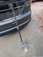 Full view of scoop leaning against vehicle showing handle and scoop head