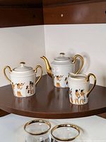 Three-piece tea set including teapot, creamer, and sugar bowl with Egyptian-themed decoration and gold trim.