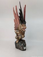 Front three-quarter view of carved wooden dragon on base