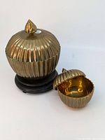 Pair of brass lidded bowls with wooden stand, side by side showing size difference and lid design.