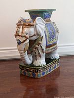 Side angle of ceramic elephant plant stand showing intricate painted details and tassels
