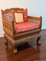 Front view of the Indian wedding chair showing detailed wood carving, red seat cushion and three pillows.