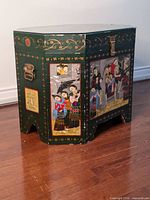 Full view of the chest showing two painted panels and side handle, dark green base with gold and floral designs.