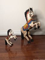 Pair of handcarved Mexican wooden horses, one larger (30 inch) and one smaller (14 inch), both handpainted with colorful saddles and black manes.