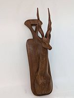 Front view of hand carved wooden antelope head wall decor showing detailed carving and natural wood grain.