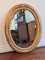 Full view of oval mirror leaning against wall