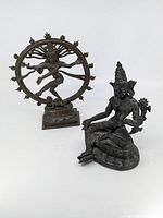 Pair of bronze statues on a white background showing Nataraja Shiva statue and seated figure.