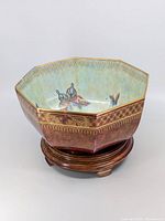 Octagonal Wedgwood bowl on wooden stand, showing overall shape, lustre finish, and butterfly decorations.