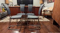 Four matching Daystrom mid-century modern dinette chairs arranged in a seated group with visible seats, backs, and chrome tubular frames on a wood floor.