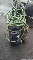 Full view of blue Campbell Hausfeld air compressor with green hose coiled on handle showing overall used condition.