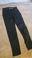 Front view of the black Carhartt women's fitted pants laid flat showing front pockets and slim tapered legs.