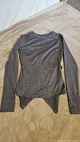 Front view of the heather gray long sleeve shirt laid flat to show overall condition and asymmetrical hem design.