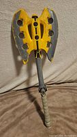 Yellow and gray Nerf battle axe toy standing upright showing wear and foam material.