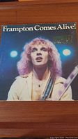 Front cover of 'Frampton Comes Alive!' album with Peter Frampton and stage lights