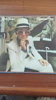 Front cover of the Elton John Greatest Hits vinyl record showing Elton John in white suit and hat.