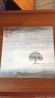 Front cover of the Genesis Wind & Wuthering vinyl record showing a single tree and stylized title text.