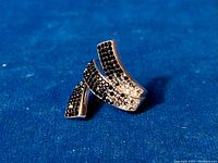 Curved modernist sterling silver statement ring with clear and black rhinestones shown from front angle.