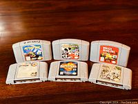 Six Nintendo 64 game cartridges displayed on wood surface: Mickey's Speedway, Extreme-G, Monaco GP, Turok, Battletanx, and Wave Race.