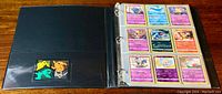 Exterior view of the black binder opened to an empty pocket and the first page of sleeved Pokemon cards.