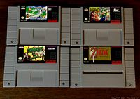 Four Super Nintendo game cartridges on a wooden surface, showing front labels for Zelda, Zombies Ate My Neighbours, Mario is Missing, and Bugs Bunny Rabbit Rampage