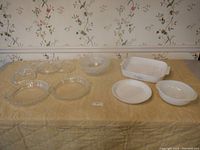 Lot setup showing all dishes and lids on yellow tablecloth with wallpaper background.
