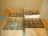 Four open boxes containing a total of 51 quart-sized glass jars, view from top.