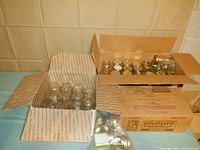 Open box showing multiple clear glass regular pint Mason jars, some with lids and rings visible