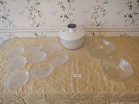 Photo showing the full lot: OXO salad spinner, two decorative glass salad bowls, eight floral etched salad plates arranged on a table with a floral wallpaper background.