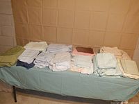 Wide shot of all 11 sheet sets neatly folded on table showing variety of colors and patterns.
