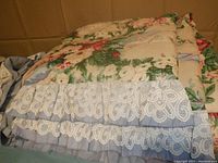 Folded vintage floral comforter with lace ribbon trim edges, showing detailed construction and colors.
