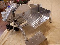 Photo of the Rival vintage electric food slicer showing the blade, food carriage, metal frame, and power cord.