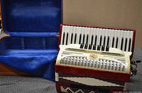 Accordion and open hard carrying case with blue velvet interior displayed side by side