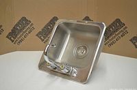 Front angle view of stainless steel bar sink with attached faucet showing basin and drain assembly.