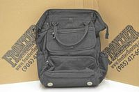 Front view of black Lug Via bag showing multiple zippered compartments, handles, and bag body.