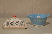 Butter dish and citrus juicer side by side on a beige surface against a beige tile background.