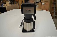 Front view of Bunn coffee maker including stainless steel carafe and power cord