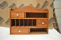 Front view of solid wood cubby organizer showing arrangement of three drawers, vertical dividers, and shelves.