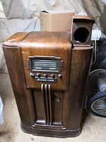 Full view of General Electric G-97 radio console wooden cabinet with side speaker section showing circular opening and overall wood finish condition.