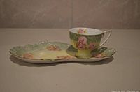 Green floral teacup and matching saucer shown from side view, highlighting floral design and shape.